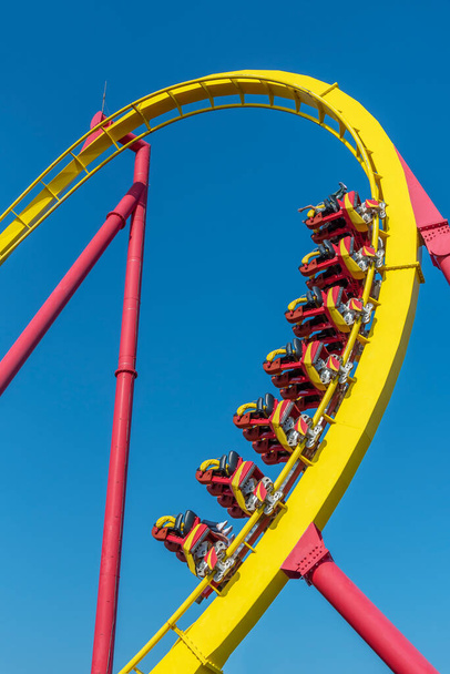 Rollercoaster ride in theme park (against blue sky) - Foto, Imagen