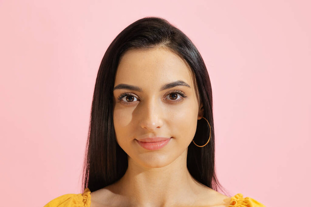 Calm look. Closeup face of young beautiful girl, student looking at camera isolated on pink background. Concept of beauty, art, fashion, youth, healthy lifestyle. Copyspace for ads, text - Φωτογραφία, εικόνα