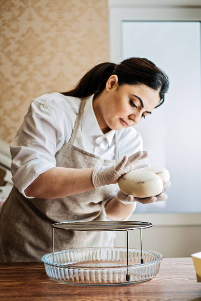 Orta Asya 'lı Arap kadın pasta şefi Mirror Glaze Mousse keki yapıyor. Bayan Ortadoğu profesyonel pastacı. Pasta dekoratörü. Şekerleme, şekerci dükkanı ve gastronomi. - Fotoğraf, Görsel