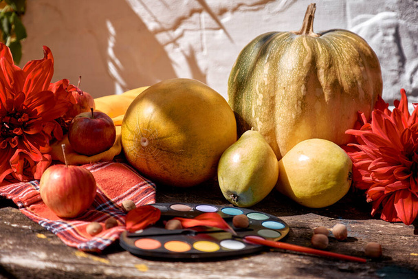 Koncepcja Święta Dziękczynienia. Jesienny jarmark estetyczny: żółte owoce, warzywa i jasne farby pędzlem, dynią, gruszkami, jabłkiem i melonem. Jesienna martwa natura z czerwoną georginą, współczesne cienie - Zdjęcie, obraz