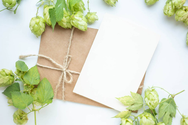 Minimalistic card mockup with hop branch, flower, craft envelope, blossom, flat lay, top view - Foto, Imagen