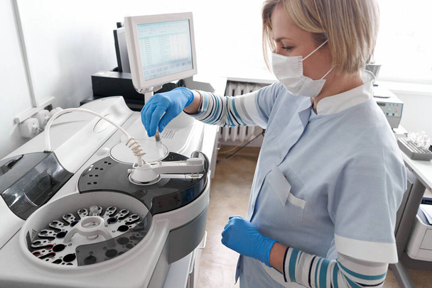 Vrouwelijke arts die een centrifuge gebruikt in een ziekenhuis - Foto, afbeelding