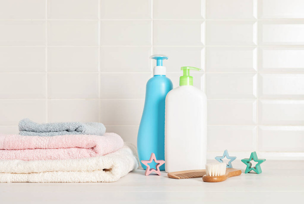 Set van baby toiletartikelen, kind biologische hygiëne en bad accessoires, douchegel, shampoo, etherische olie, handdoek in de badkamer - Foto, afbeelding