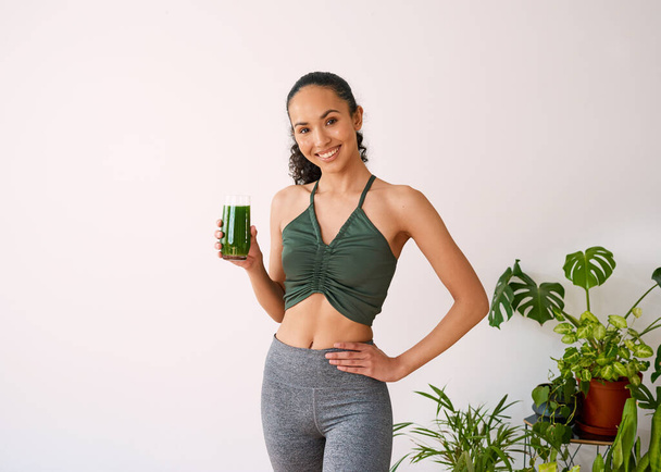 A beautiful multi-ethnic woman smiles with green juice - spinach, kale, vitamans. High quality photo - Foto, imagen
