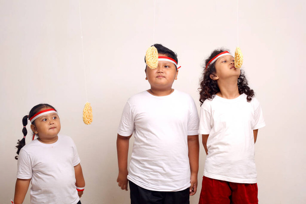 Asian kids celebrating indonesian independence day with cracker eating contest. - Foto, Imagem