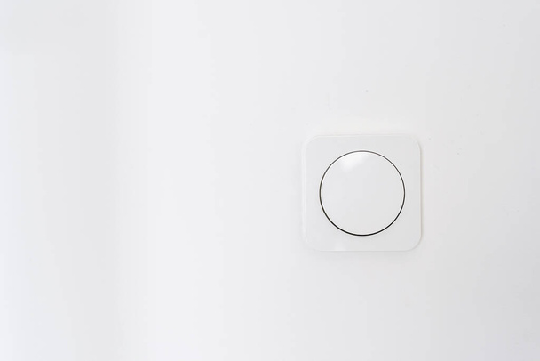 Cropped view of white light switch on wall in modern living room. Apartment after renovation. Energy saving. Safety and comfort concept. House interior design details - 写真・画像