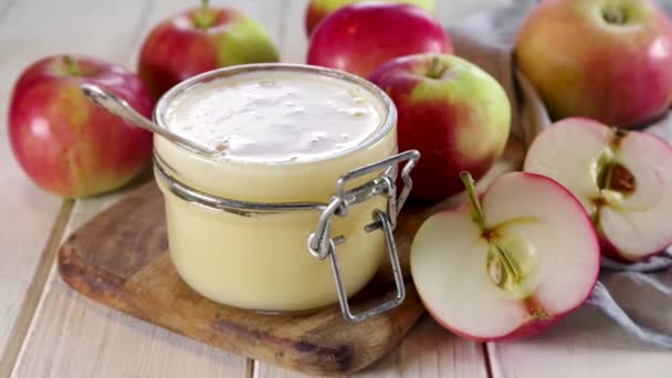 Homemade Organic Applesauce, healthy apple sauce in small jar with fresh summer apples on wooden white background - Filmati, video