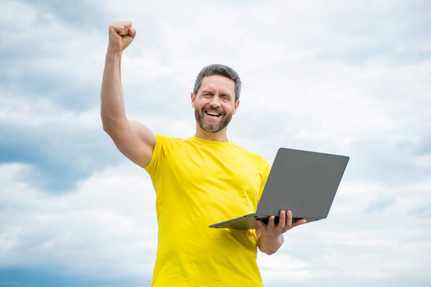 happy man working online on laptop on sky background. - Φωτογραφία, εικόνα