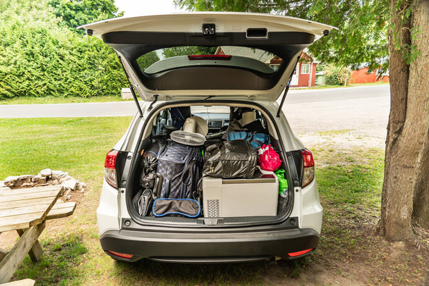 Travel on car with camping luggage packed at the full car trunk, holiday concept. Outdoor activities items. Camping and exploring in summer season. Adventures and travel suv vehicle.  - Fotó, kép