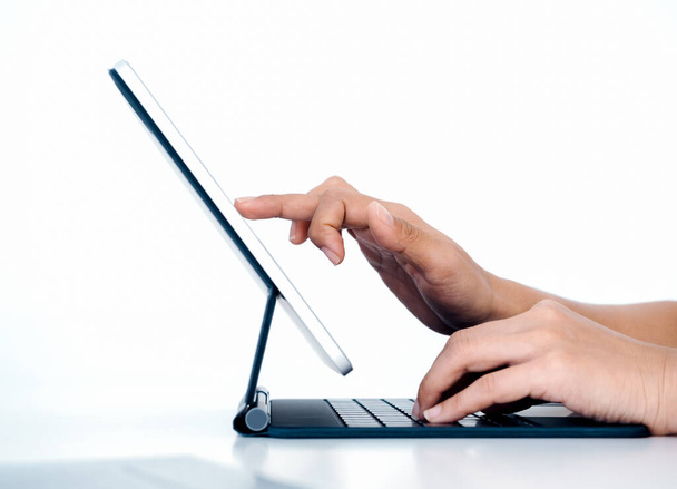 Person's finger touching, drawing on digital tablet screen while typing on keyboard computer with another hand isolated on white background with copy space, side view. Work with technology. - Foto, immagini
