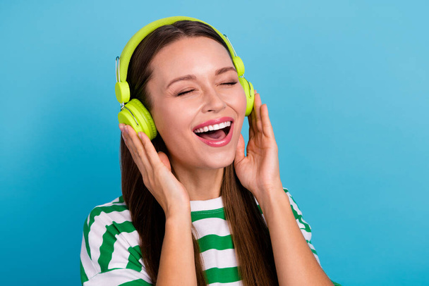 Photo of joyful young lady sing wear earphones green t-shirt isolated on bright blue color background. - Foto, Imagem