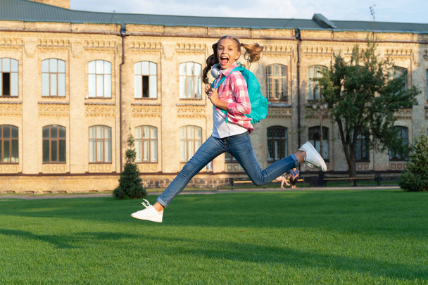 Happy teenage girl jumping in school yard outdoors, back-to-school. - Foto, imagen