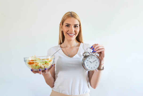 Молода жінка тримає годинник і здорову їжу з салату Переривчаста концепція посту. Час схуднути, їсти контроль або час на концепцію дієти
. - Фото, зображення