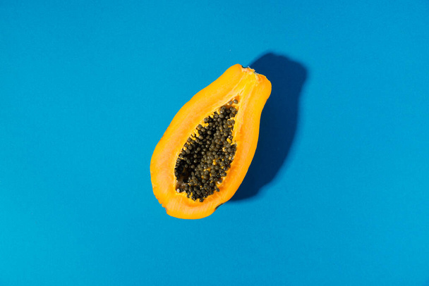 single papaya fruit cutter on half on blue background. copy space - Foto, immagini