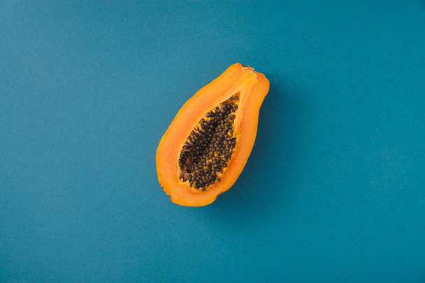 single papaya fruit cutter on half on blue background. copy space - Photo, Image