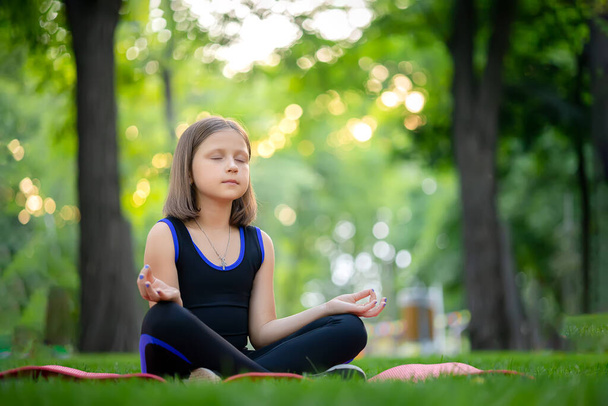 meditation in the park in the lotus position little girl meditates and relaxes - Foto, imagen