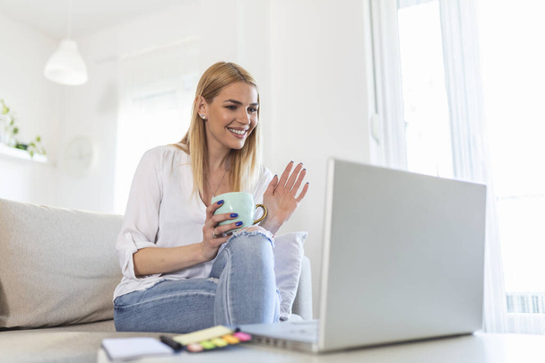 Young woman waving at laptop and talking to her friends via video call, girl student talking by video conference call, female teacher trainer tutoring by webcam, online training, e-coaching concept - Photo, image