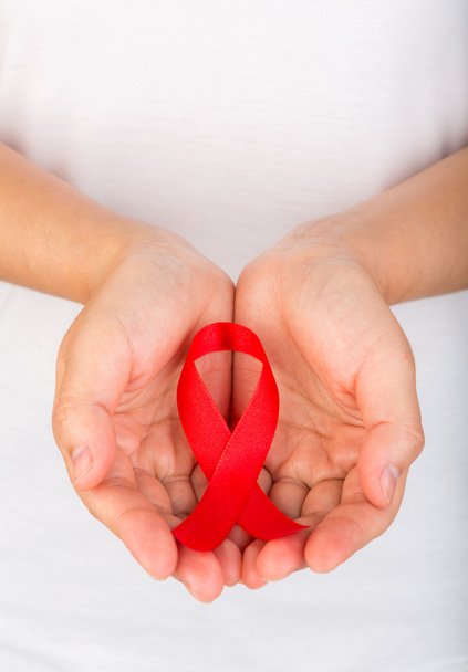Female hands holding red AIDS awareness ribbon - Foto, afbeelding