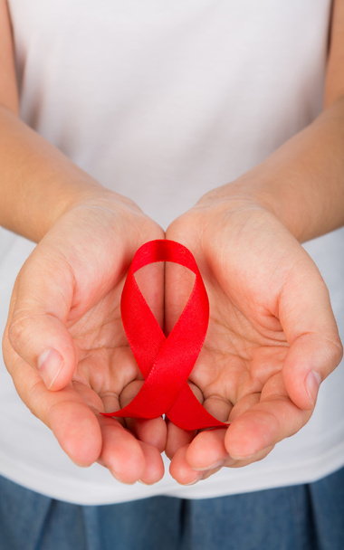 Female hands holding red AIDS awareness ribbon - Фото, изображение