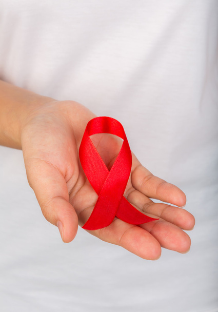 Female hands holding red AIDS awareness ribbon - 写真・画像