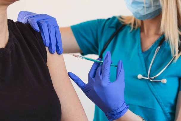 患者の肩に注射やワクチンを投与する女性医師または看護師。インフルエンザやウイルスのパンデミックに対する予防接種。予防接種の概念 - 写真・画像