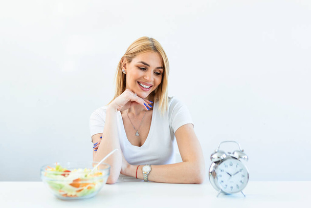Young woman holding clock and Healthy food of salad Intermittent fasting concept. Time to lose weight , eating control or time to diet concept. - 写真・画像