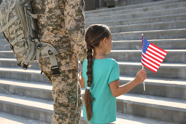 Soldier and his little daughter with American flag outdoors. Veterans Day in USA - Photo, image
