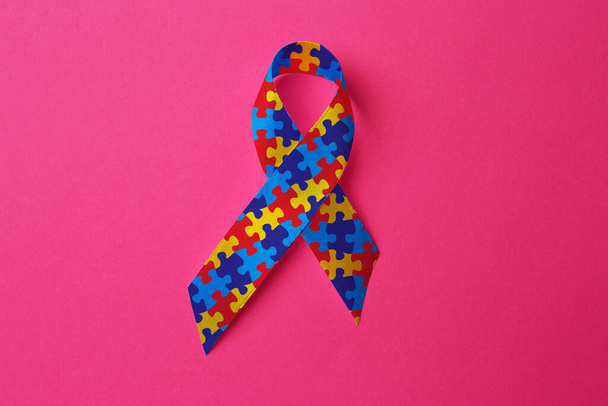 World Autism Awareness Day. Colorful puzzle ribbon on pink background, top view - Fotó, kép