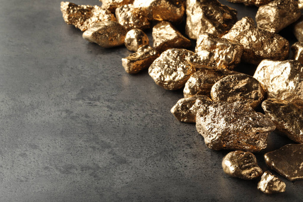 Pile of gold nuggets on grey table, space for text - Foto, imagen