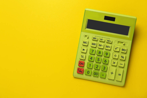 Green calculator on yellow background, top view. Space for text - Фото, изображение