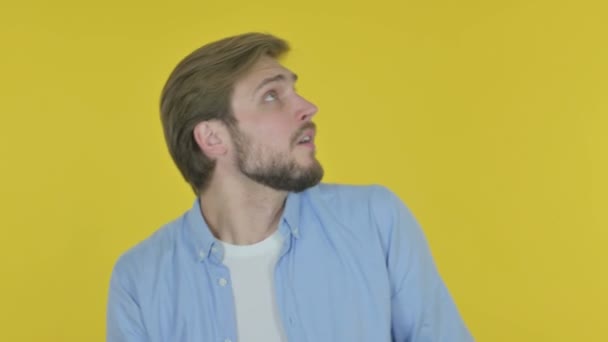 Casual νεαρός άνδρας αισθάνεται φοβισμένος, φοβισμένος στο κίτρινο φόντο  - Πλάνα, βίντεο
