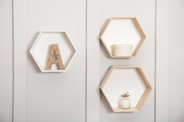 Honeycomb shaped shelves with decorative elements on white wall - Fotó, kép