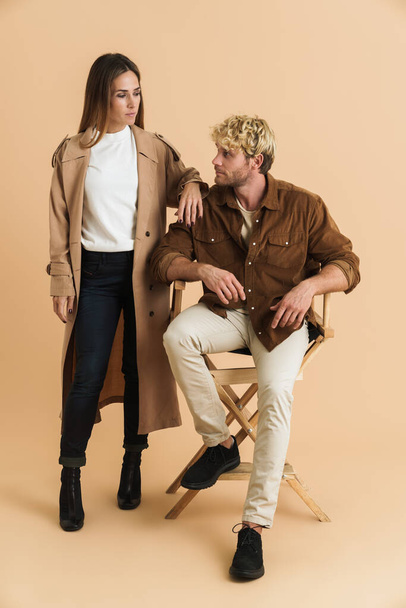 White blonde couple looking at each other while posing together isolated over beige background - Foto, afbeelding