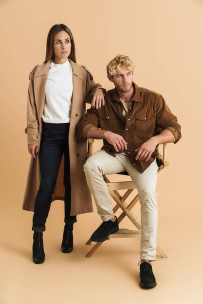White blonde couple looking aside while posing together isolated over beige background - Foto, afbeelding