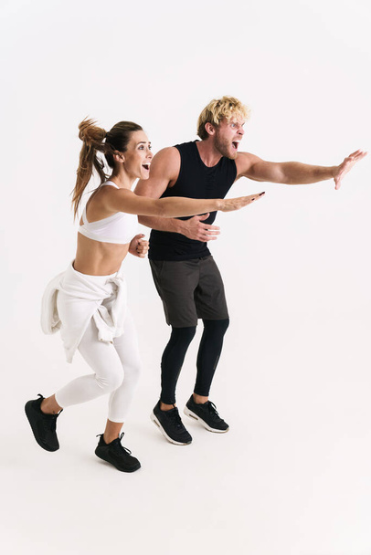 Excited couple in sportswear screaming and stretching their arms aside isolated over white background - Photo, image
