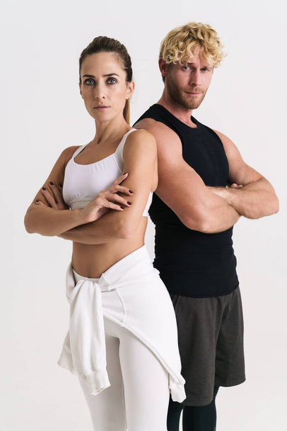 European man and woman in sportswear posing with arms crossed isolated over white background - Valokuva, kuva