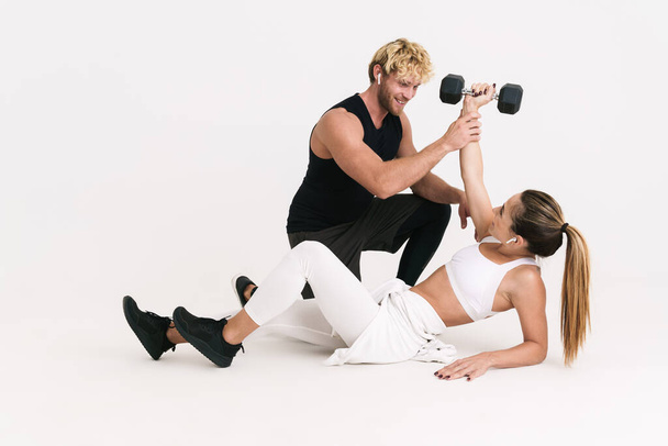 European man and woman in earphones doing exercise with dumbbell isolated over white background - Valokuva, kuva