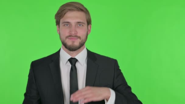 Young Adult Businessman Showing on Side on Green Background  - Felvétel, videó