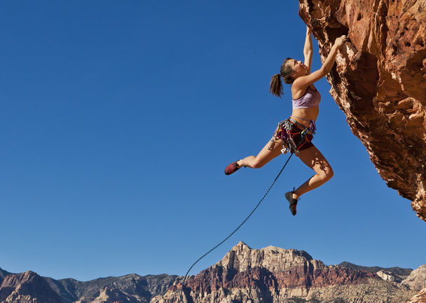 Femme grimpeuse s'accrochant à une falaise
. - Photo, image