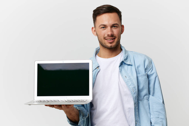 Fröhlich freundlicher, braun gebrannter, gutaussehender IT-Profi in lässigem Basic-T-Shirt mit Laptop in der Hand, der isoliert auf weißem Studiohintergrund posiert. Kopierraum Banner-Attrappe. Elektronisches Reparaturkonzept - Foto, Bild