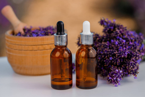Dropper bottle with lavender cosmetic oil or hydrolate against lavender flowers field as background with copy space. Herbal cosmetics and modern apothecary concept - Foto, immagini
