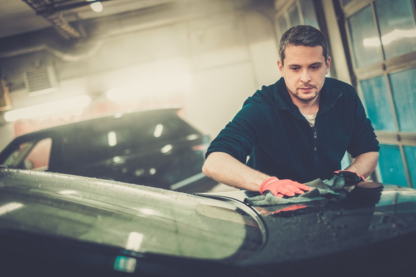 Trabajador limpiando coche en un lavado de coches
 - Foto, imagen