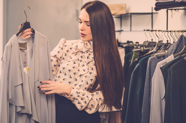 Mulher escolhendo roupas em um rack em um showroom
 - Foto, Imagem