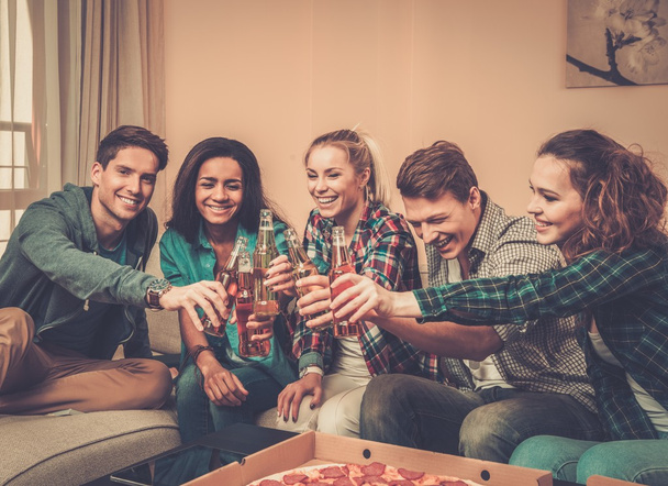 Multiethnische Freunde feiern zu Hause mit Pizza und Getränken - Foto, Bild