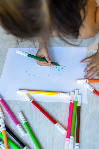 A kislány keze rajzot készít a színekkel otthon. - Fotó, kép