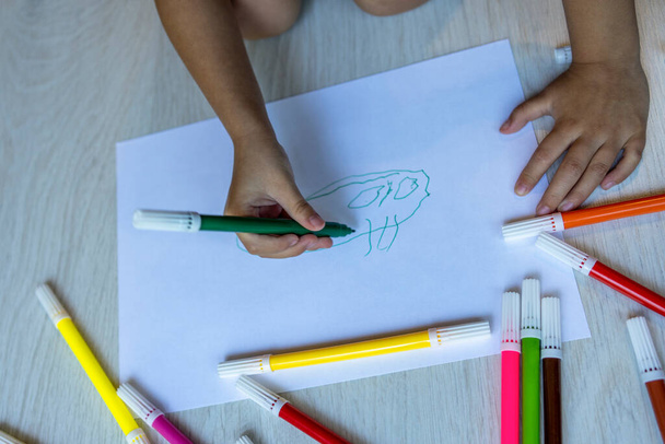 girl's hand making a drawing with colours at home - Фото, изображение