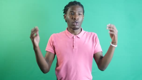 Black man raising his hands and making the i dont know sign, the sign representing of i have no idea, image of emotions and facial expressions taken in front of the green curtain - Metraje, vídeo