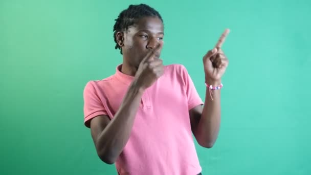 Pointing to left corner, black teenager pointing to the left of the screen with both hands, show body language and facial expressions in front of a green screen - Záběry, video