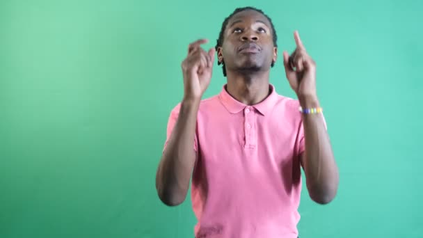 Young man pointing up, black teenager pointing with both hands above the screen, show body language and facial expressions in front of a green screen - Filmati, video
