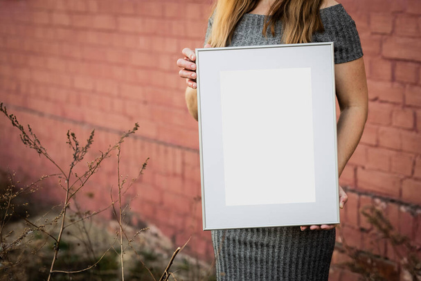 White picture frame with decorations. Mock up for your photo or text. Place your work, print art, white background, pastel color book. Photo realistic 3d illustration. Girl holding frame - Foto, Imagen